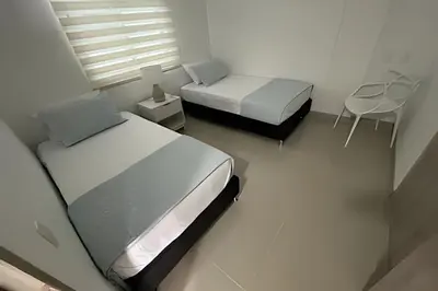 a bedroom with two beds and a table and a chair at Apartamento 2 Dormitorios Vista Mar. Piscina in Cartagena de Indias