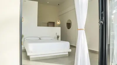 a bedroom with a white bed and a mirror at Cosamui Beach House in San Bernardo del Viento