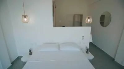 a white bed in a white room with a mirror at Cosamui Beach House in San Bernardo del Viento