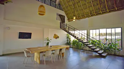 a dining room with a wooden table and a staircase at Cosamui Beach House in San Bernardo del Viento