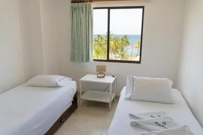 a bedroom with two beds and a window with the ocean at Coveñas - Condominio Puntepiedra Hotel in Coveñas