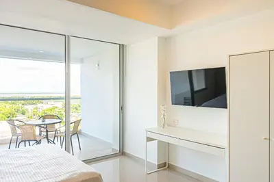 a bedroom with a bed and a tv and a table with chairs at Lujoso Apartamento Cartagena - 2 mins aeropuerto in Cartagena de Indias