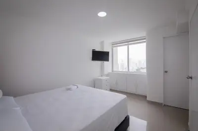 a white bedroom with a bed and a window at Exclusivo Apartamento con vista al mar in Cartagena de Indias