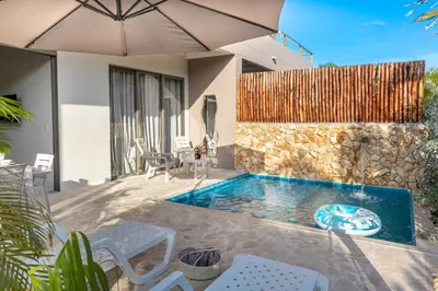 a swimming pool with an umbrella next to a house at Ilukas & Resort Villas in Coveñas