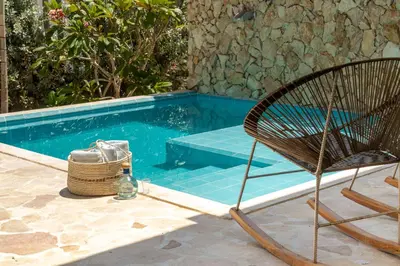 a rattan chair next to a swimming pool at Cabaña privada & Villas Iluka in Coveñitas