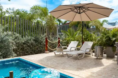 a patio with two chairs and an umbrella next to a pool at Cabaña privada & Villas Iluka in Coveñitas