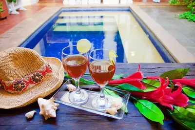 two glasses of wine and a hat next to a swimming pool at CASA AMOR, Old Town 4 BDR in Cartagena de Indias