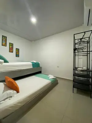 a white room with two beds and a shelf at Shekinah House in Cartagena de Indias