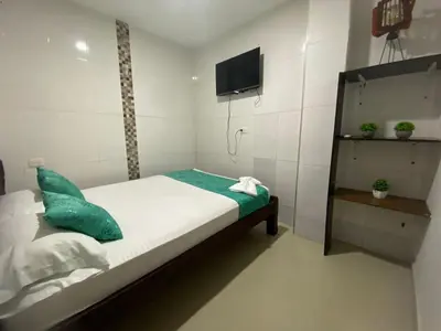 a small bedroom with a bed with a tv on the wall at Shekinah House in Cartagena de Indias