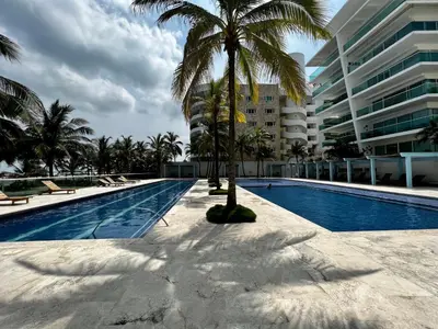 a swimming pool with a palm tree next to a building at Morros 922 Beach House in Cartagena de Indias