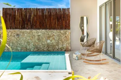 a swimming pool with two chairs and a stone wall at Villa privada en coveñas sucre in Coveñas
