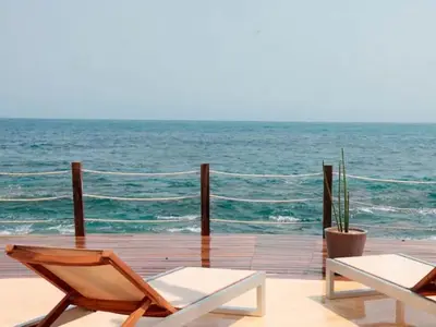 a wooden deck with a chair and a table and the ocean at Isla Pelícano in Isla Grande