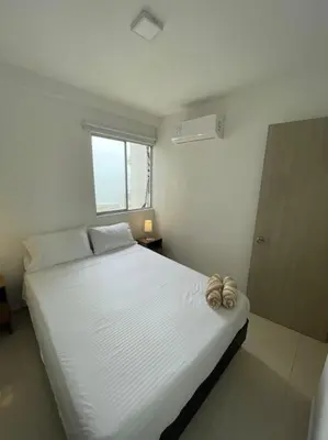 a white bed in a room with a window at Ambiente Caribe! piso 26 - 3 hab in Cartagena de Indias