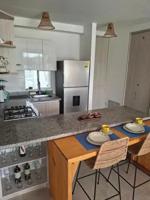 a kitchen with a counter with two chairs and a table at Apartamento Cartagena cerca a la playa in Cartagena de Indias