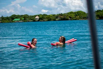 two girls are laying in the water on tubes at Hotel Coral Sand Islas Del Rosario in Isla Grande