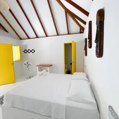 a white bedroom with a white bed and a yellow door at Hotel Coral Sand Islas Del Rosario in Isla Grande