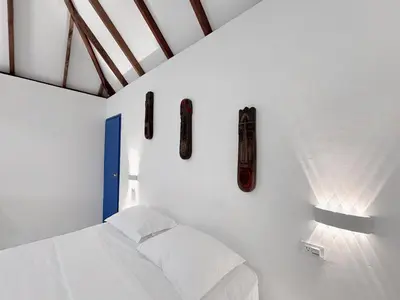 a bedroom with a bed and two masks on the wall at Hotel Coral Sand Islas Del Rosario in Isla Grande