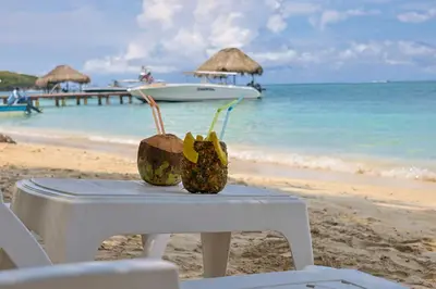 a table on the beach with a boat in the water at Hotel Coral Sand Islas Del Rosario in Isla Grande