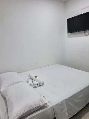 a white bed with white towels and a tv at Hotel Corales del Mar in Cartagena de Indias