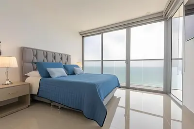 a bedroom with a blue bed and large windows at Awesome Sea View and Historic Center “Morros City” in Cartagena de Indias