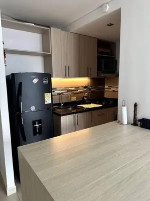 a kitchen with a black refrigerator and wooden cabinets at Luminoso y confortable in Cartagena de Indias