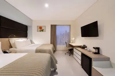 a hotel room with two beds and a desk and a television at Wyndham Garden Barranquilla in Barranquilla