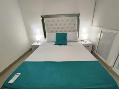 a bedroom with a large white bed with a green pillow at EM2-1G APARTAMENTO DE 2 HAB CERCA AL MAR ZONA RESIDENCIA WIFi Y PARQUEADERO in Cartagena de Indias