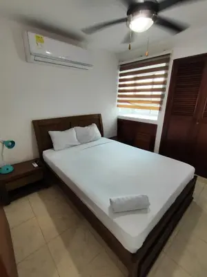 a bedroom with a large bed with white sheets and a window at EM3-1G APARTAMENTO DE 1 HAB EN ZONA RESIDENCIAL AIRE ACONDICIONADO Wifi Y PARQUEADERO in Cartagena de Indias
