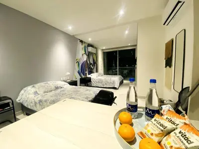 a room with two beds and a table with a bowl of oranges at Espectacular apto Loft NUEVO- Frente al Hilton Pozos Colorados in Santa Marta