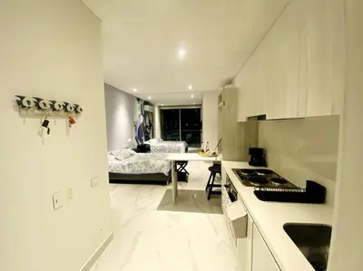 a white kitchen with a table and a bed at Espectacular apto Loft NUEVO- Frente al Hilton Pozos Colorados in Santa Marta
