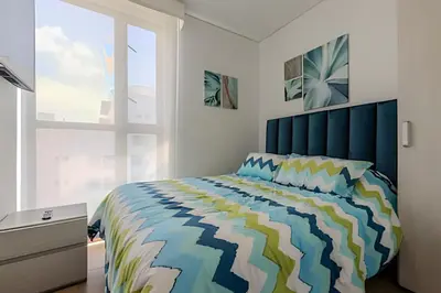 a bedroom with a bed with a blue headboard and a window at Espectacular Vista al Mar and Historic Center 2BR in Cartagena de Indias