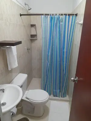 a bathroom with a toilet and a blue shower curtain at Apartamento Cartagena Torices 50 in Cartagena de Indias