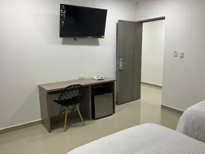 a bedroom with a chair and a television on the wall at Hotel fenix in Barranquilla