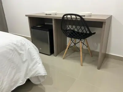 a desk with a black chair next to a bed at Hotel fenix in Barranquilla
