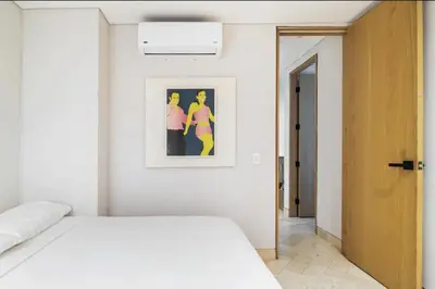 a bedroom with a white bed and a picture on the wall at Cozy New Apartment in the Old City in Cartagena de Indias