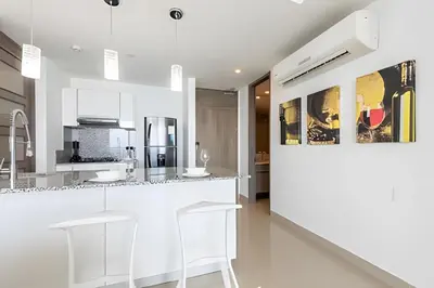 a white kitchen with a counter and stools at Exclusive Sea View “Morros City” 30th Fl in Cartagena de Indias