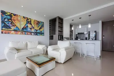 a living room with white furniture and a kitchen at Exclusive Sea View “Morros City” 30th Fl in Cartagena de Indias