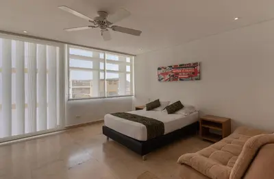 a bedroom with a bed and a couch and a ceiling fan at APARTAMENTO GRANDE CARTAGENA La Matuna in Cartagena de Indias