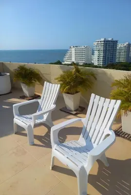 two white chairs sitting on a balcony with the ocean at Apartamento LOFT INFINITY BLUE in Santa Marta