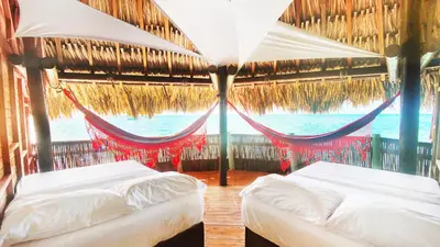 two beds in a room with a view of the ocean at Casa en el agua in Tintipan Island