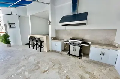a kitchen with white cabinets and a stove and stools at Piso 24 vista al mar 2BR in Cartagena de Indias