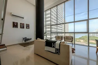 a living room with a couch and a large window at Modern 3BR duplex Apt. Great view and location in Cartagena de Indias