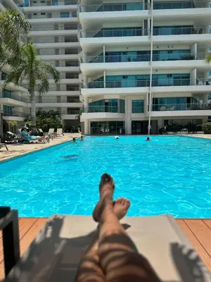 a person laying on a chaise lounge next to a swimming pool at Apartamento con Salida al Mar en Condominio Turístico y Hotel Sonnesta Cartagena, in Cartagena de Indias