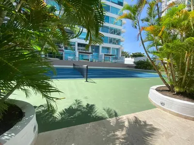 a tennis court with palm trees in front of a building at Apartamento con Salida al Mar en Condominio Turístico y Hotel Sonnesta Cartagena, in Cartagena de Indias
