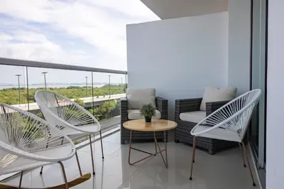 a balcony with white chairs and a couch and a table at Apto en Morros Epic Cartagena in Cartagena de Indias