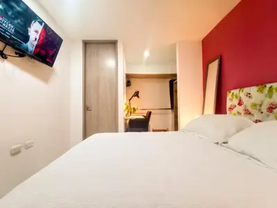 a bedroom with a white bed and a red wall at Lindo apto cerca del Malecón con patio y terraza in Barranquilla