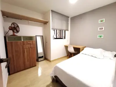 a bedroom with a bed and a desk with a fan at Lindo apto cerca del Malecón con patio y terraza in Barranquilla