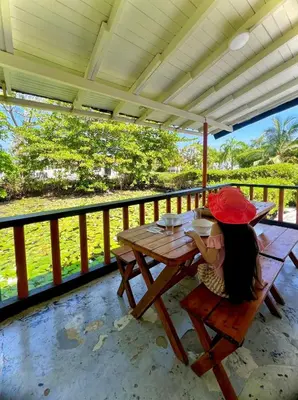 a girl sitting at a picnic table on a porch at Cerca a Coveñas- Cabaña El Paraiso - Mar - Arena in San Antero
