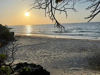 a beach with the sun setting over the ocean at La Felicidá in Cartagena de Indias