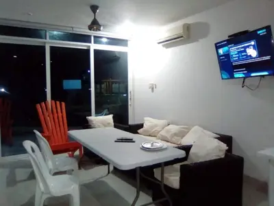 a living room with a table and a couch and a tv at Condominio de Cabañas Cangrejo Azul in El Bobo